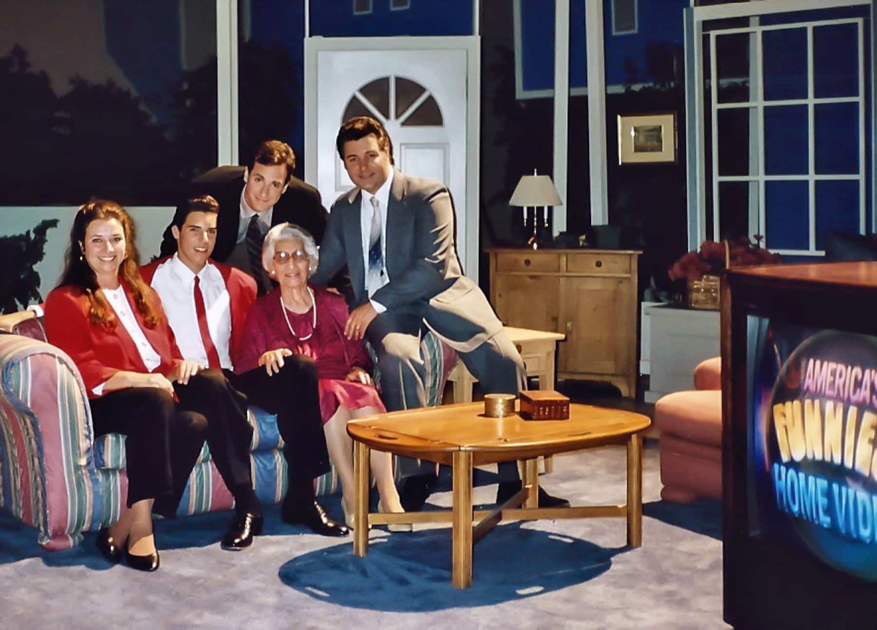 Five people pose in a living room set, with a TV showing "AMERICA'S FUNNIEST HOME VIDEOS."