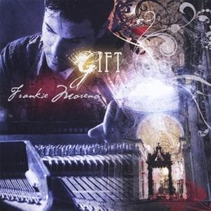 A man looks down at a piano keyboard, with "GIFT" and "Frankie Moreno" text, and a cathedral dome.