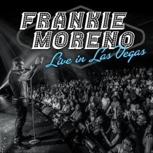 A man sings into a microphone on stage, facing a large audience, with "FRANKIE MORENO Live in Las Vegas" text.