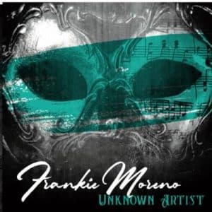 A black and white masquerade mask with a teal band across the eyes, featuring musical notes and text "Frankie Moreno UNKNOWN ARTIST".