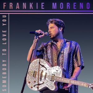 A man in a patterned shirt sings into a microphone, holding a white and gold electric guitar. "FRANKIE MORENO SOMEBODY TO LOVE YOU"