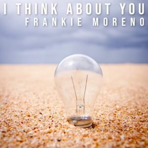 A clear lightbulb stands upright in light brown sand under a cloudy sky, with text "I THINK ABOUT YOU FRANKIE MORENO".