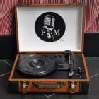 An open brown and black portable record player with a "F&M" logo and microphone on the lid.