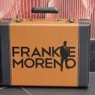 A brown and black briefcase with gold clasps and handle, featuring "FRANKIE MORENO" and a man's silhouette.