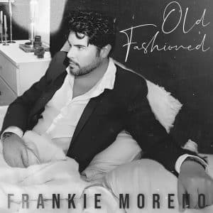 A black and white photo of a man with dark hair and a beard, wearing a suit jacket and white shirt, reclining on pillows. Text reads "Old Fashioned" and "FRANKIE MORENO".