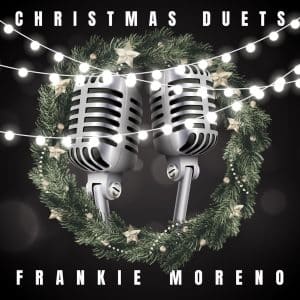 Two silver microphones are centered in a Christmas wreath with lights, "CHRISTMAS DUETS" and "FRANKIE MORENO" text.