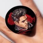 A black circular pop socket with an illustration of Elvis Presley's head and shoulders, "Elvis" in red.
