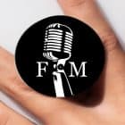 A black pop socket with a white vintage microphone and the letters "F" and "M" on a person's finger.
