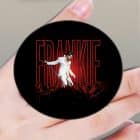 A hand holds a black pop socket with "FRANKIE" in red lights above a singer in a white suit on stage.